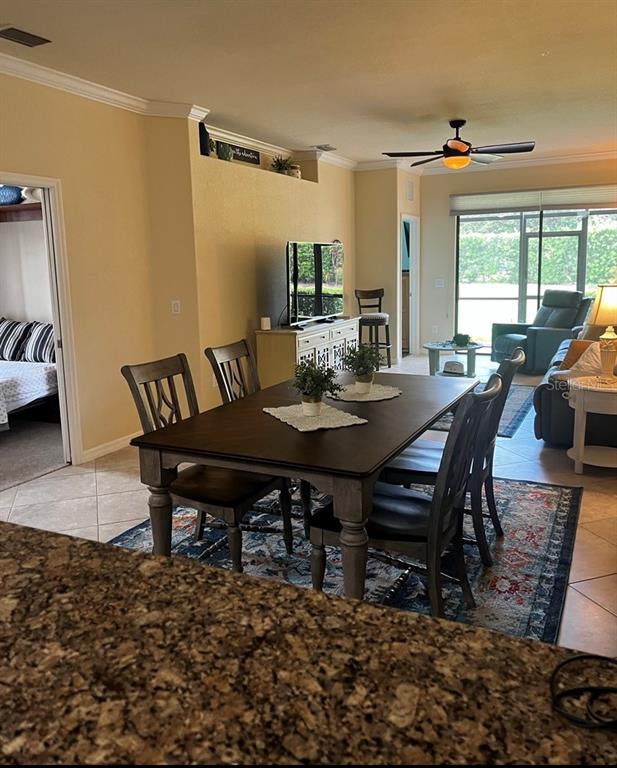 A dining area with a wooden table and chairs sits in an open-concept living space — 6760 WILLOWSHIRE WAY, BRADENTON, FL