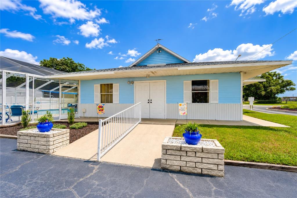 A light blue building features a concrete ramp leading to double doors and two planters — 34910 HAPPINESS WAY, ZEPHYRHILLS, FL