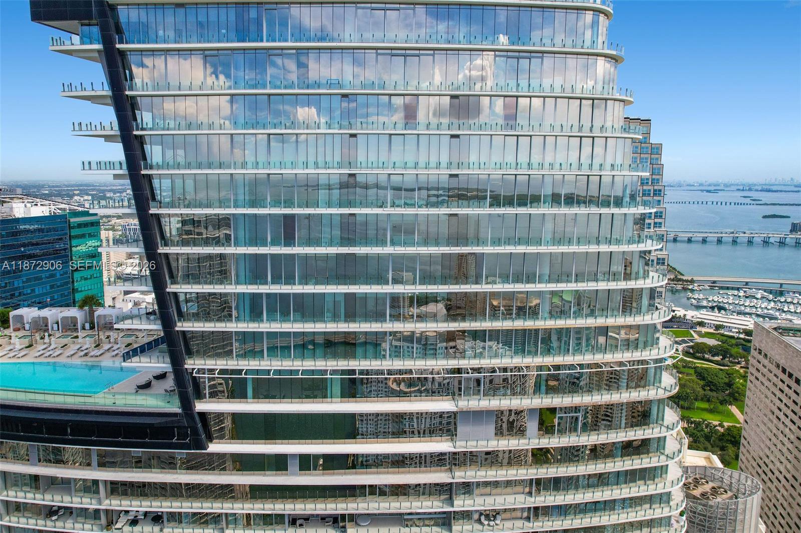 An exterior view of a modern glass high-rise building featuring multiple balconies and a pool — 300 Biscayne Blvd Way, Miami FL 33131, MIAMI, FL