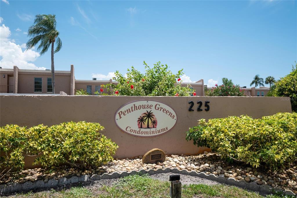 A tan wall displays the Penthouse Greens Condominiums sign and the number 225 — 225 COUNTRY CLUB DRIVE UNIT E343, LARGO, FL