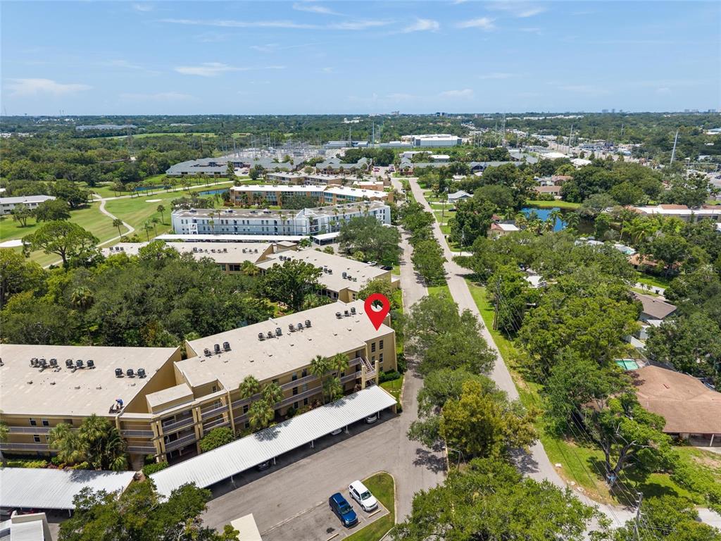 An aerial view shows a multi-story apartment building with covered parking and surrounding green space — 225 COUNTRY CLUB DRIVE UNIT E343, LARGO, FL