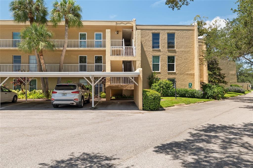 A three-story apartment building with a covered parking area and palm trees in front — 225 COUNTRY CLUB DRIVE UNIT E343, LARGO, FL