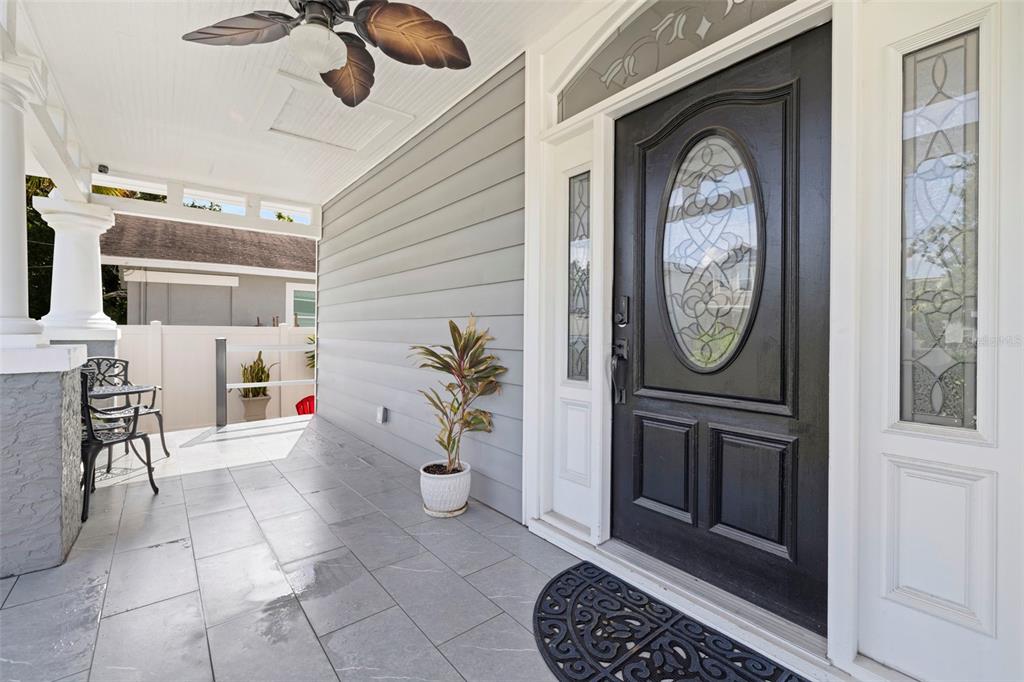 A covered front porch features gray tile flooring, a black door, and a ceiling fan — 2526 W UNION STREET, TAMPA, FL