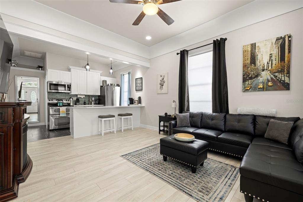A living room with light wood floors, a black sectional sofa, and an open kitchen — 2526 W UNION STREET, TAMPA, FL
