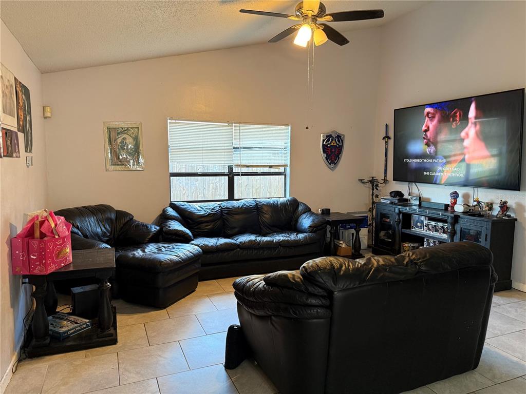 A living room with black leather furniture, a large television, and a ceiling fan — 3916 MAGNOLIA LAKE LANE, ORLANDO, FL