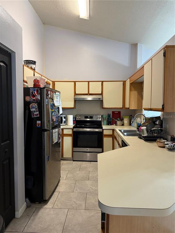 A kitchen features light-colored cabinets, stainless steel appliances, a tiled floor, and laminate countertops — 3916 MAGNOLIA LAKE LANE, ORLANDO, FL