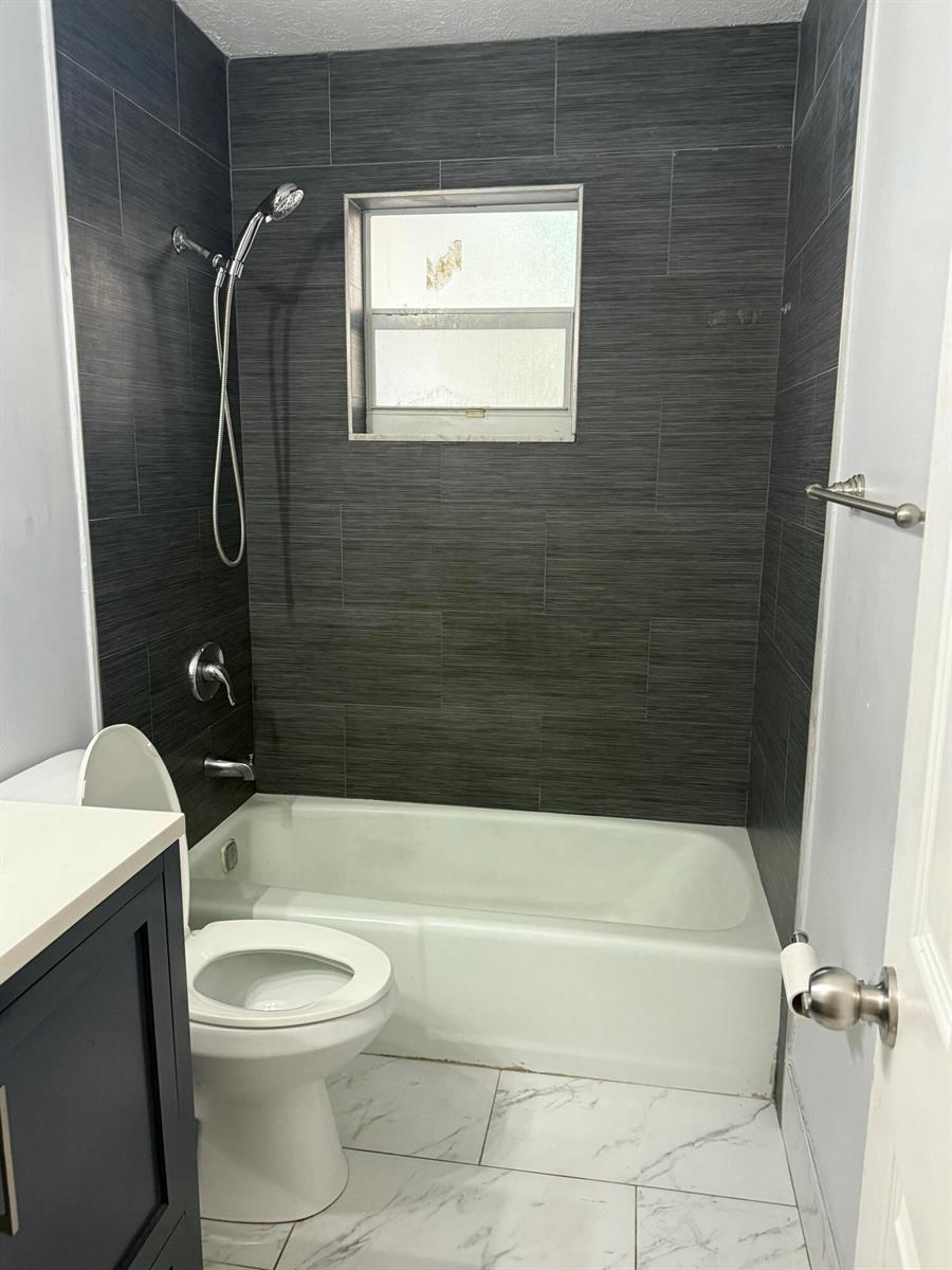 A bathroom features a bathtub with dark gray tile walls and white marble-look floor tiles — 1503 N J Street # A, FL 33460, FL