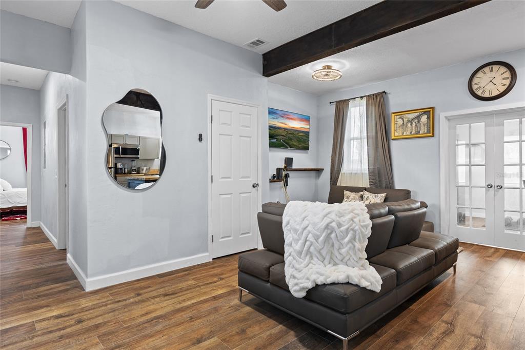 A living room features a brown sectional sofa, wood-look flooring, a wall mirror, and a clock — 234 W MAGNOLIA STREET, APOPKA, FL