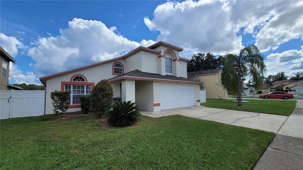 A two-story suburban house with a white garage, stucco exterior, and a front lawn — 3011 BRANSBURY COURT, KISSIMMEE, FL