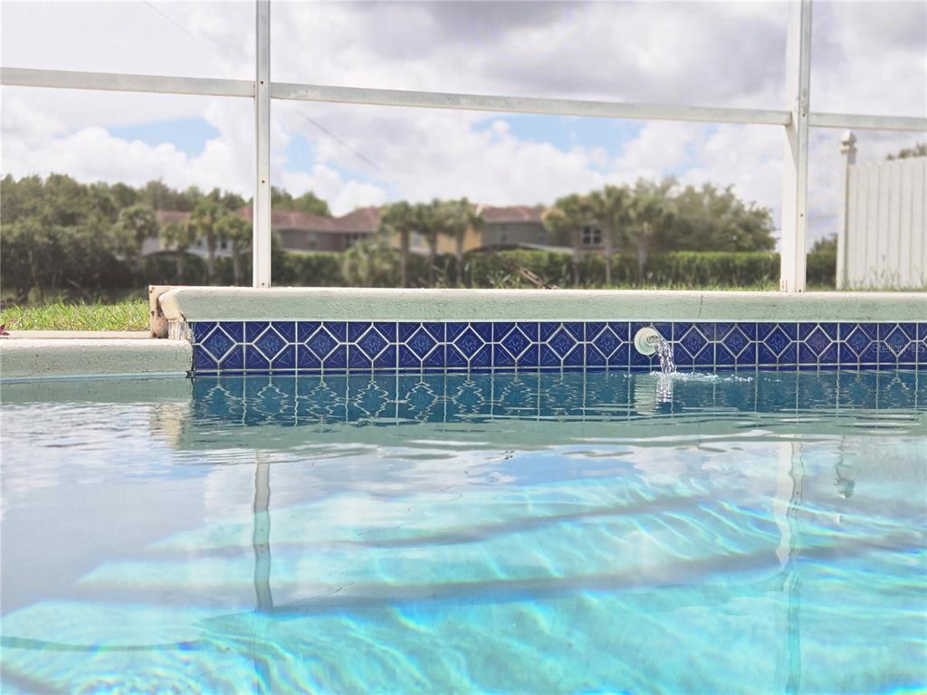 A swimming pool with blue decorative tile trim and a water feature — 3011 BRANSBURY COURT, KISSIMMEE, FL
