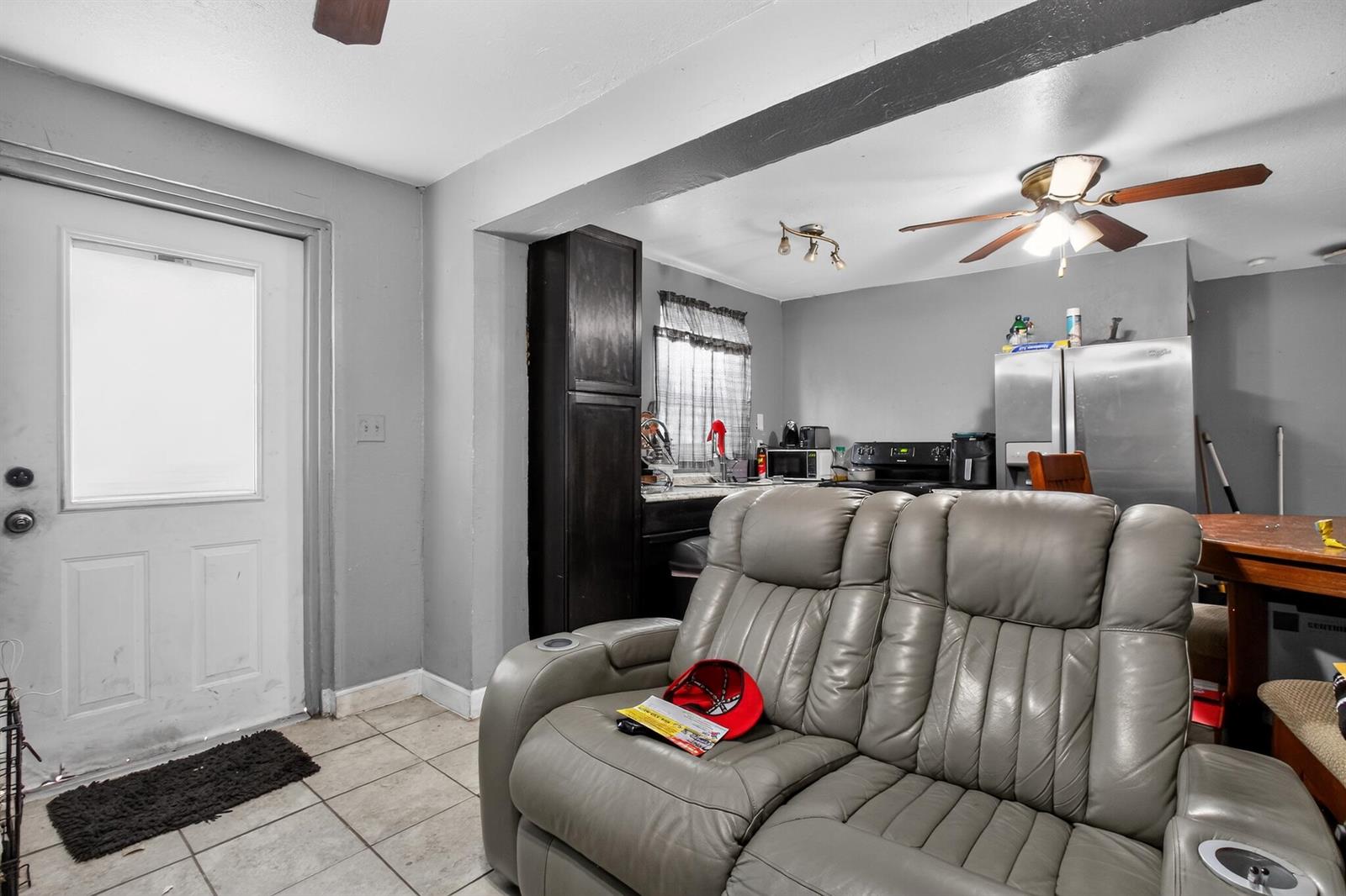 A gray leather loveseat sits in a living area open to a kitchen with appliances — 608 NW 15th Avenue, Pompano Beach FL 33069, POMPANO BEACH, FL