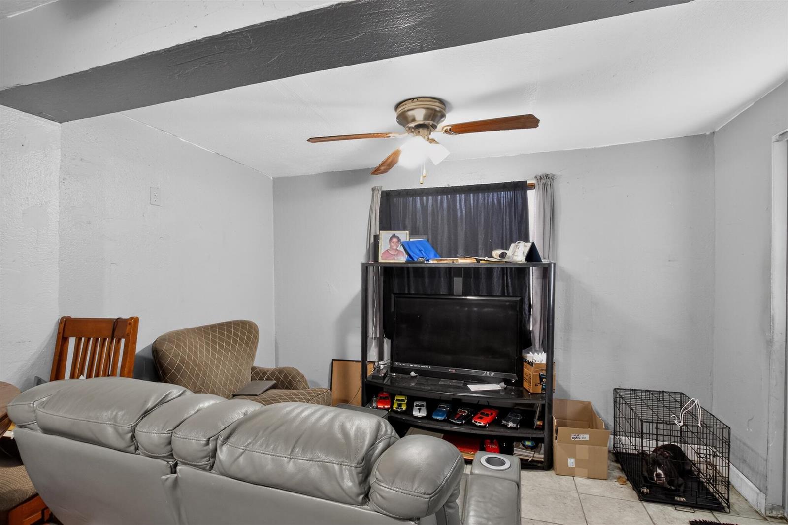 A living room features a gray sofa, an armchair, a television stand, and a dog crate — 608 NW 15th Avenue, Pompano Beach FL 33069, POMPANO BEACH, FL