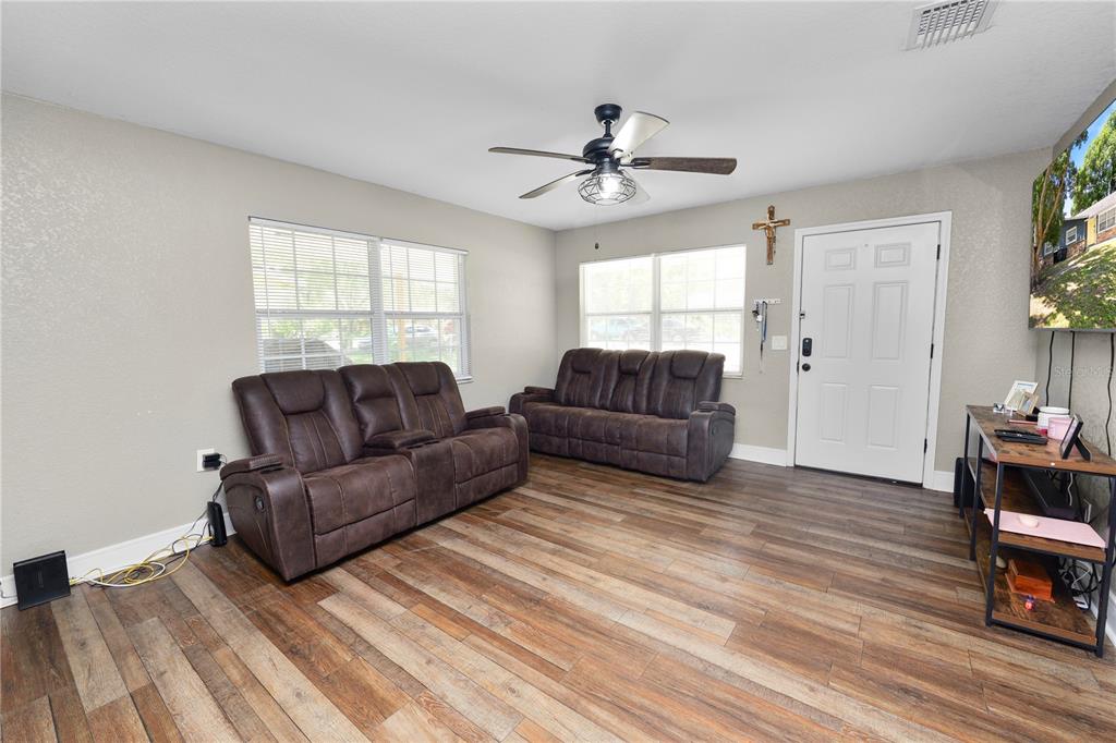 A living room features wood-look flooring, two brown reclining sofas, and a ceiling fan — 4561 DAVID DRIVE, BARTOW, FL