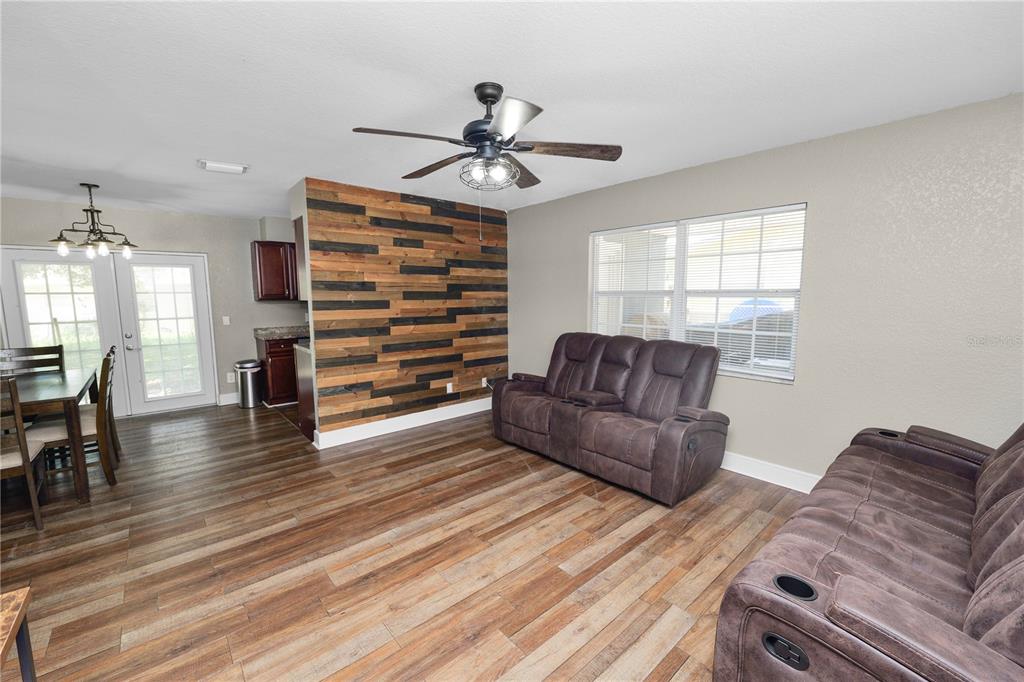 A living room with wood-look flooring, a wood-plank accent wall, and two brown reclining sofas — 4561 DAVID DRIVE, BARTOW, FL