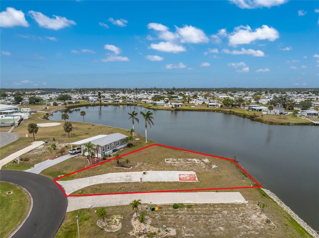 An aerial view shows a vacant waterfront lot outlined in red next to a house — 6257 BUNTING LANE, ENGLEWOOD, FL