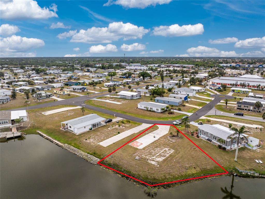 An aerial view shows a vacant waterfront lot outlined in red next to a house — 6257 BUNTING LANE, ENGLEWOOD, FL