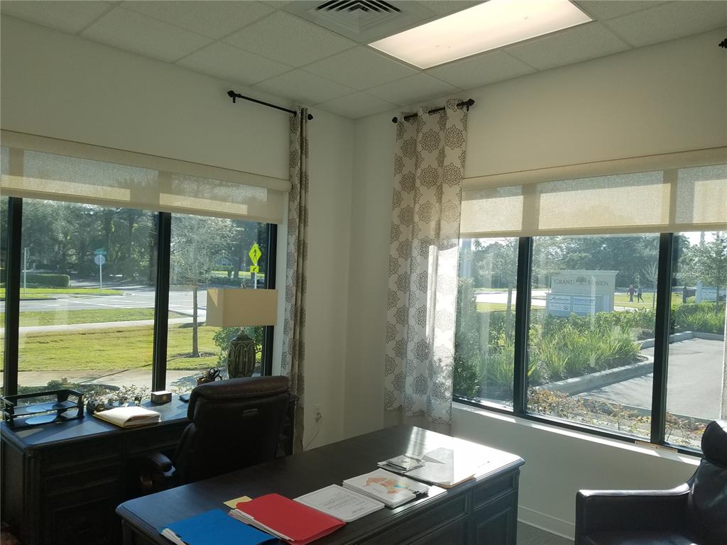 An office with two desks, large windows, patterned curtains, and a view of a street — 2298 COLBERT LANE, PALM COAST, FL