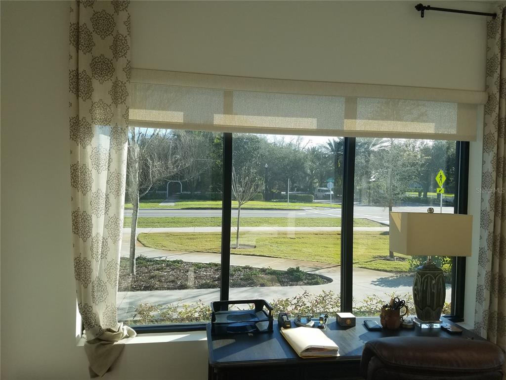 A desk sits in front of a large window overlooking a street and grassy area — 2298 COLBERT LANE, PALM COAST, FL