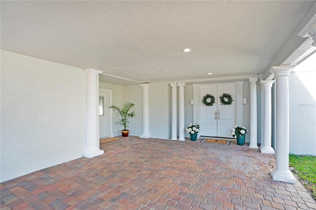 A covered entryway features a brick paver floor, white columns, and double front doors — 2117 OCEAN DRIVE, NEW SMYRNA BEACH, FL