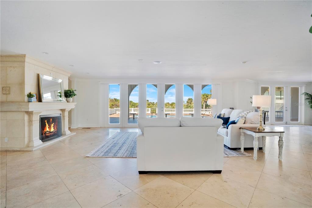 A spacious living room features a stone fireplace, white furniture, and large glass patio doors — 2117 OCEAN DRIVE, NEW SMYRNA BEACH, FL