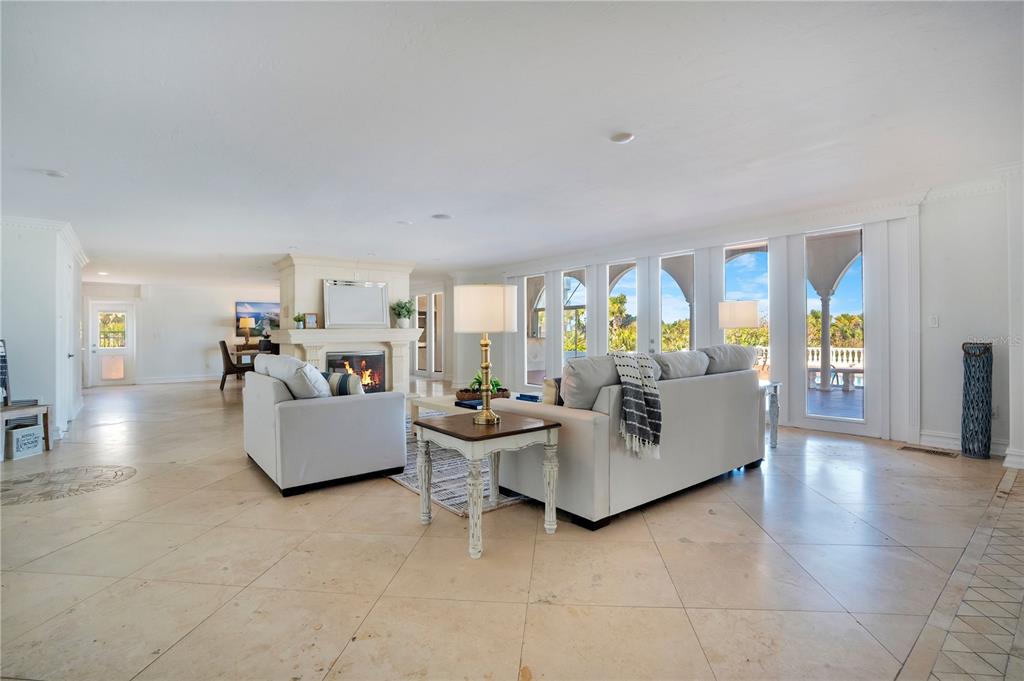 A spacious living room features a stone fireplace, light tile flooring, and large glass doors — 2117 OCEAN DRIVE, NEW SMYRNA BEACH, FL