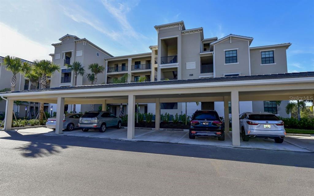 A multi-story apartment building with a covered parking structure in the foreground — 17626 GAWTHROP DRIVE UNIT 206, BRADENTON, FL