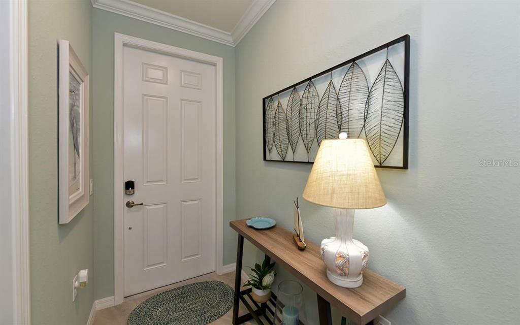 A light green entryway features a white door, a console table, and wall art — 17626 GAWTHROP DRIVE UNIT 206, BRADENTON, FL