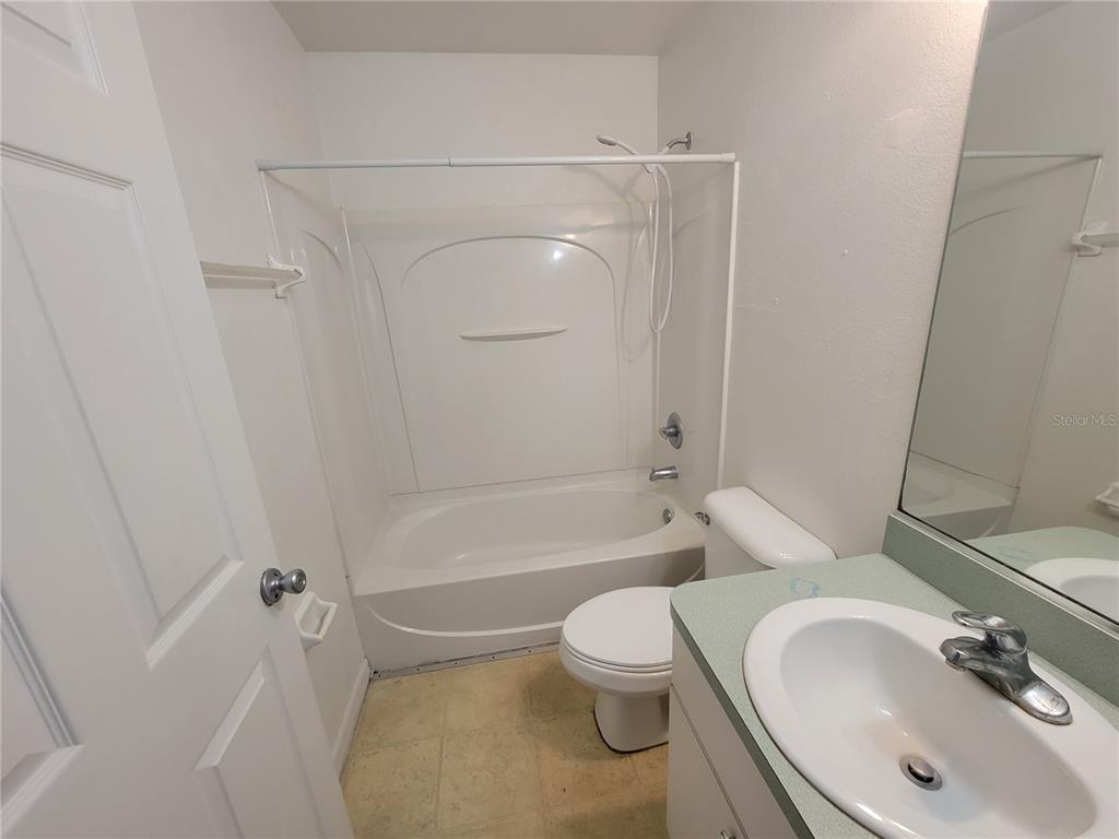 A small bathroom features a white tub-shower combo, a toilet, and a vanity with sink — 15755 SW 33RD AVE ROAD UNIT 1, OCALA, FL