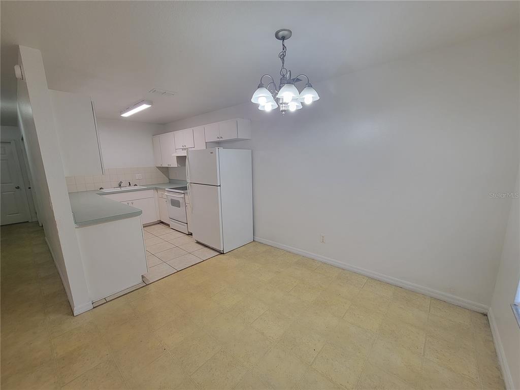 A kitchen with white cabinets, white appliances, and a dining area with a chandelier — 15755 SW 33RD AVE ROAD UNIT 1, OCALA, FL