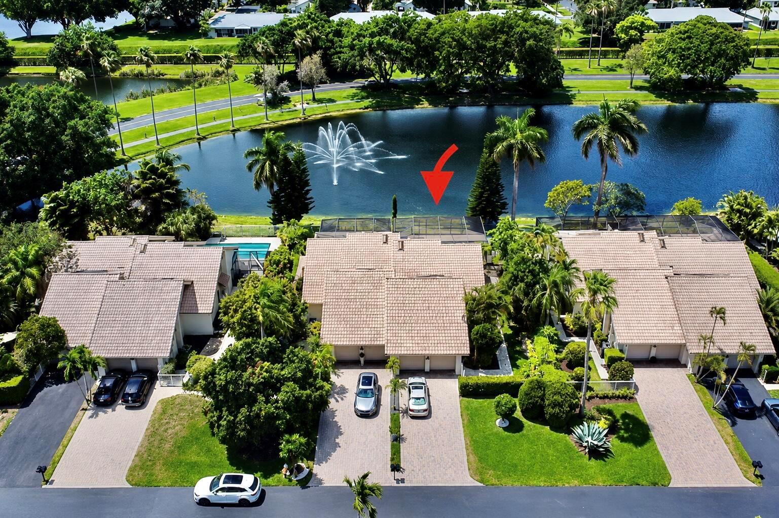 An aerial view of a residential complex with tiled roofs, driveways, and a lake fountain — 9708 Erica Court, Boca Raton FL 33496, BOCA RATON, FL