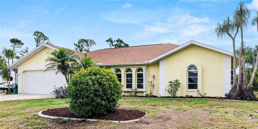 A yellow single-story house with a two-car garage and palm trees in the front yard — 831 COLUMBIA STREET, PORT CHARLOTTE, FL