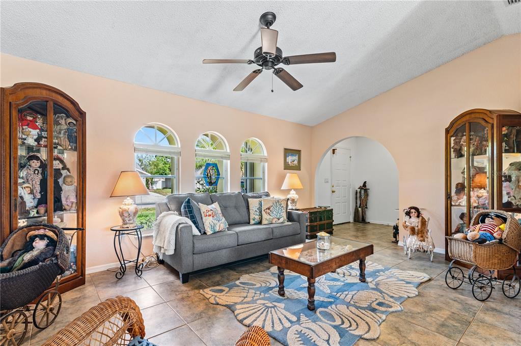 A living room features a gray sofa, a shell-patterned rug, and two large display cabinets — 831 COLUMBIA STREET, PORT CHARLOTTE, FL