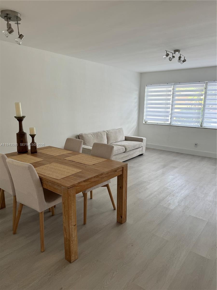 A dining area with a wooden table and chairs sits adjacent to a living room — 330 SE 2nd St # 104F, Hallandale Beach FL 33009, HALLANDALE BEACH, FL