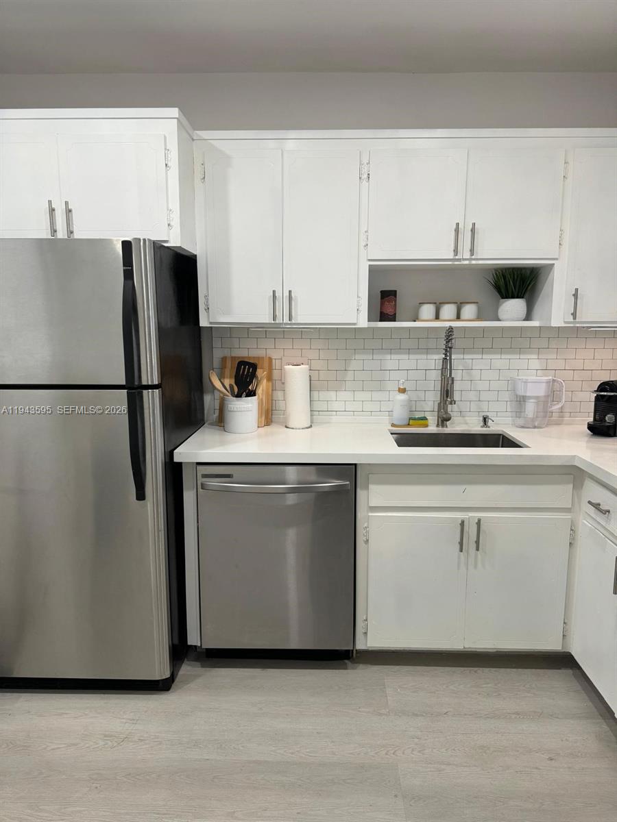 A kitchen features white cabinets, stainless steel appliances, a white subway tile backsplash, and countertops — 330 SE 2nd St # 104F, Hallandale Beach FL 33009, HALLANDALE BEACH, FL