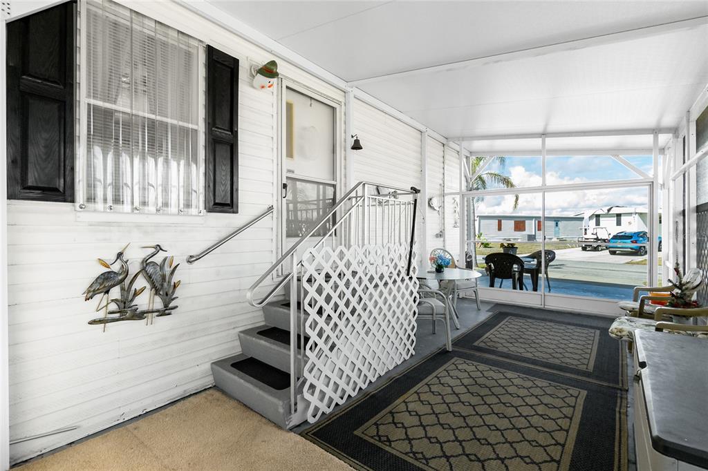 A covered porch features a set of stairs with a lattice railing and outdoor furniture — 7594 RATAN CIRCLE, PORT CHARLOTTE, FL