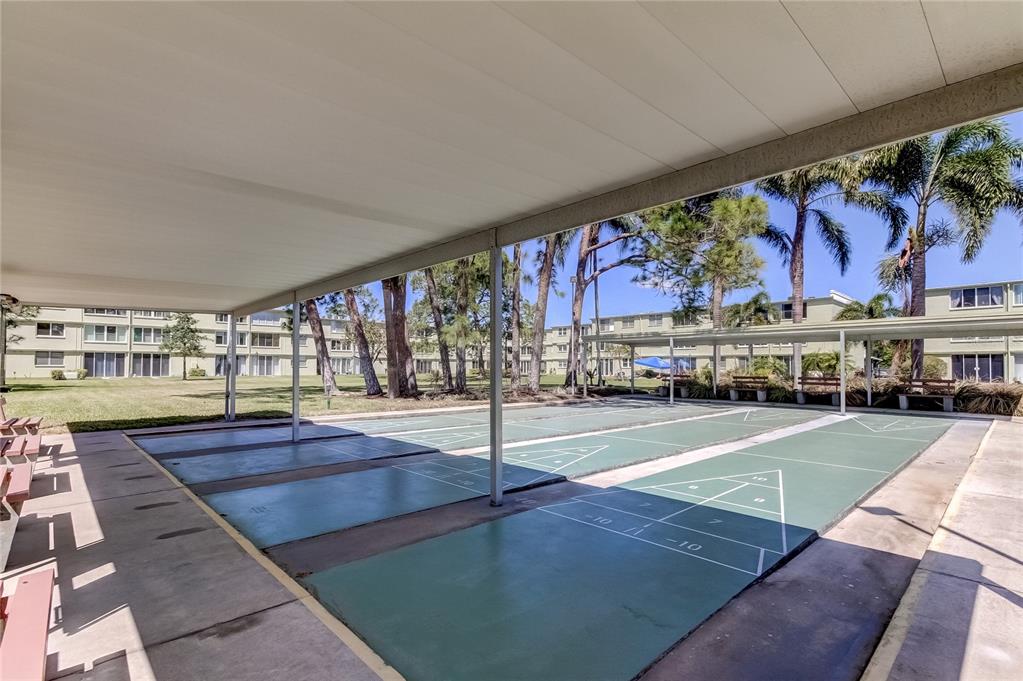 A covered outdoor shuffleboard court sits in front of a multi-story apartment building — 4890 BAY STREET NE UNIT 323, ST PETERSBURG, FL