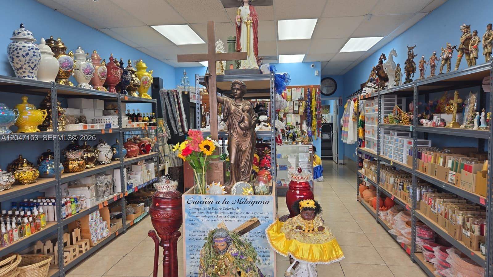 The interior of a retail shop features shelves filled with religious statues, candles, and ceramics — MIAMI, FL