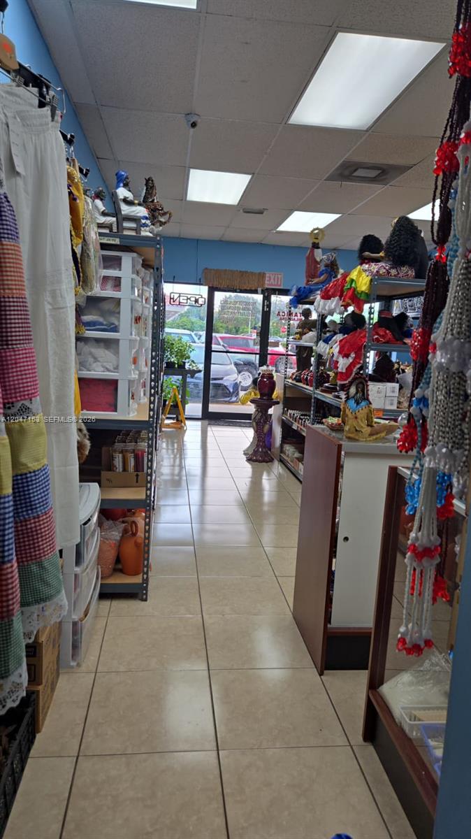 A retail shop interior features tiled floors, shelving units with various items, and a glass door — MIAMI, FL