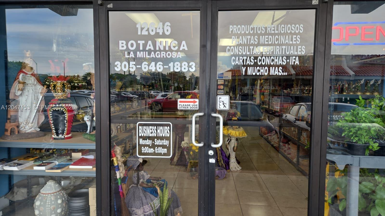 The exterior view shows the glass double doors of a botanica shop with business information — MIAMI, FL