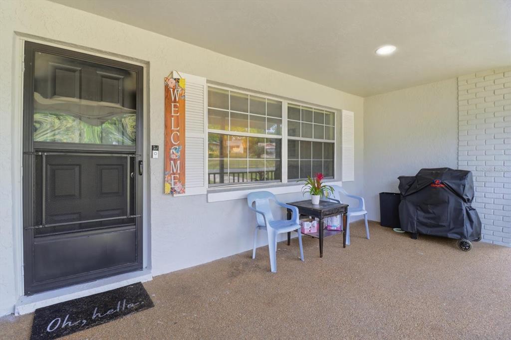 A covered front porch features a screen door, a small seating area, and a grill — 3721 N GOLDENCUP TERRACE, BEVERLY HILLS, FL