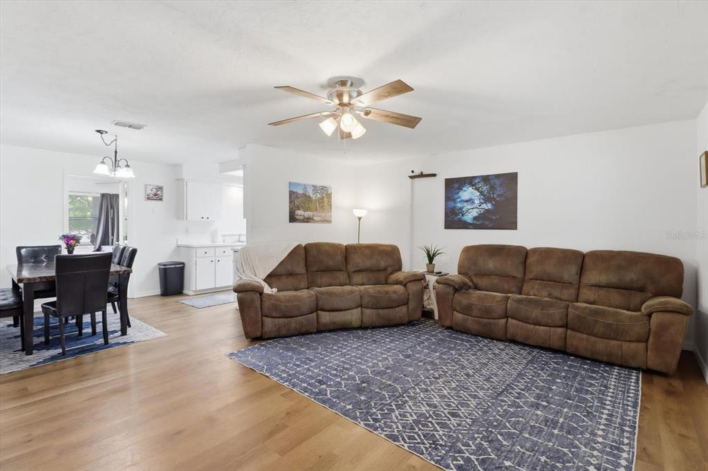 A living room with two brown sofas, a blue area rug, and an adjacent dining area — 3721 N GOLDENCUP TERRACE, BEVERLY HILLS, FL