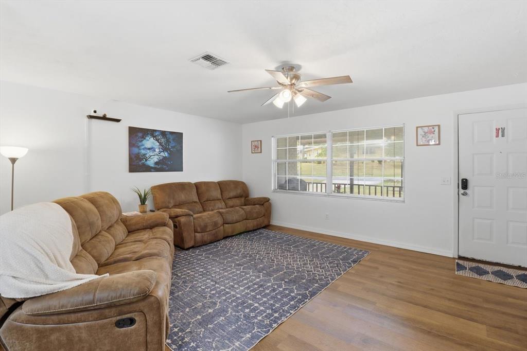 A living room features brown reclining sofas, a patterned area rug, and a ceiling fan — 3721 N GOLDENCUP TERRACE, BEVERLY HILLS, FL