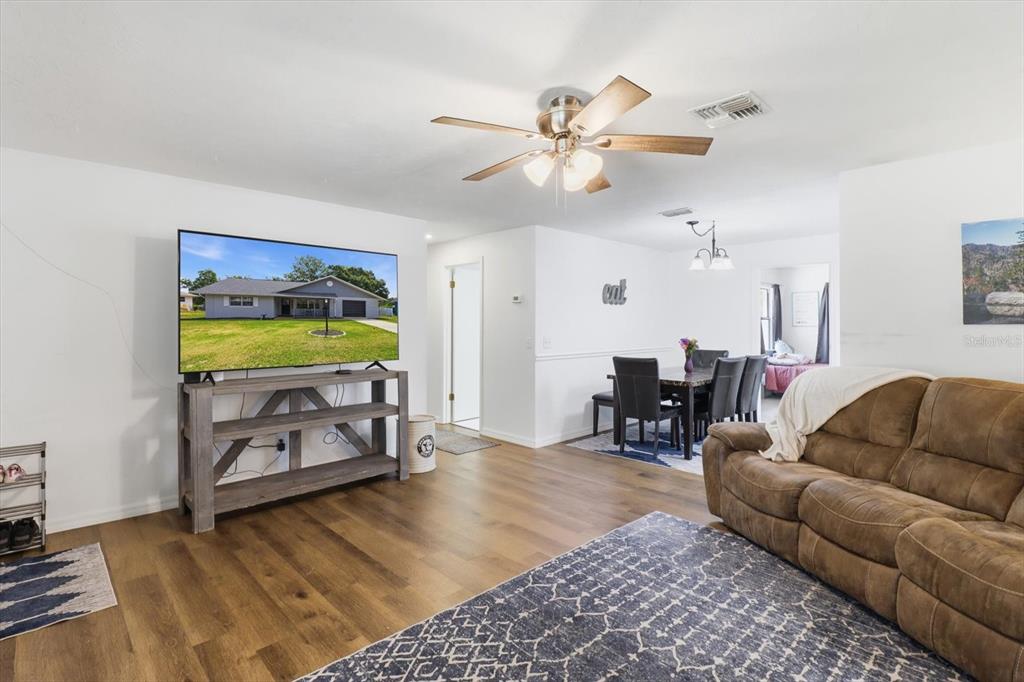 A living room with wood-look flooring, a ceiling fan, and a dining area beyond — 3721 N GOLDENCUP TERRACE, BEVERLY HILLS, FL