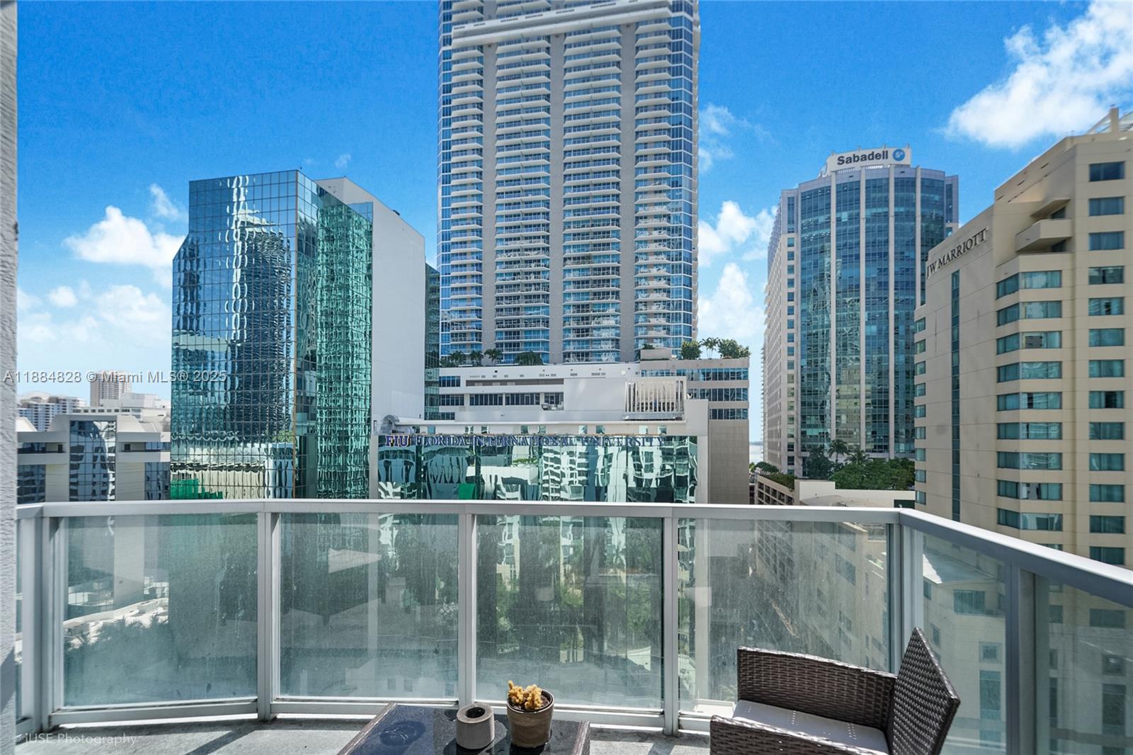 A balcony with a glass railing overlooks a dense urban skyline of high-rise buildings — 1060 Brickell Ave # 1203, Miami FL 33131, MIAMI, FL