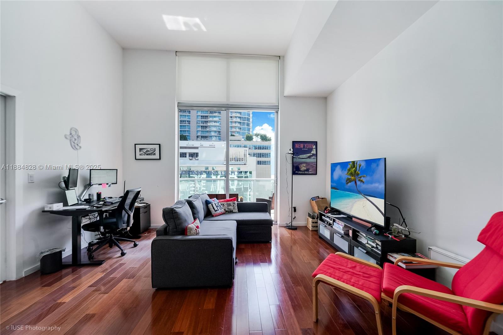 A living room with hardwood floors, a sectional sofa, a desk, and a balcony view — 1060 Brickell Ave # 1203, Miami FL 33131, MIAMI, FL