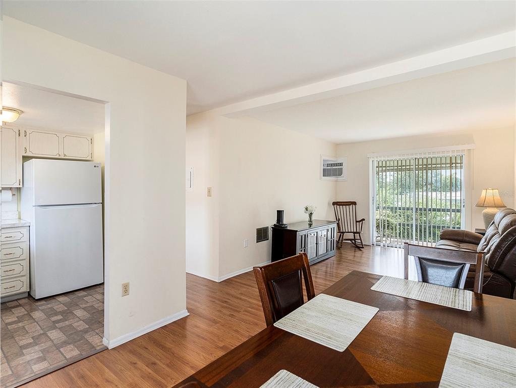 A dining area opens into a living room with a sliding glass door and kitchen — 1859 RESTFUL DRIVE UNIT L26, BRADENTON, FL