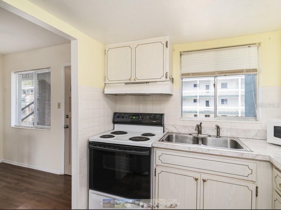 A kitchen with white cabinets, a black electric stove, and a double-basin stainless steel sink — 1859 RESTFUL DRIVE UNIT L26, BRADENTON, FL