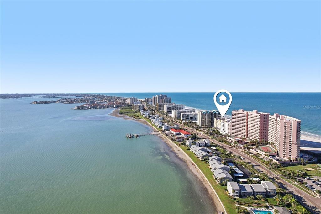 An aerial view shows a coastal beach with high-rise condominiums and a residential neighborhood — 1270 GULF BOULEVARD UNIT 701, CLEARWATER, FL