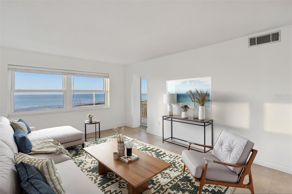 A bright living room features a white sofa, a wooden coffee table, and an ocean view — 1270 GULF BOULEVARD UNIT 701, CLEARWATER, FL