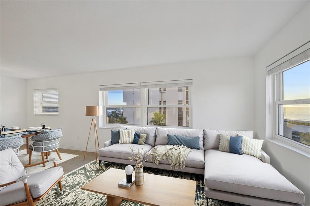 A living room features a light gray sectional sofa, a wooden coffee table, and large windows — 1270 GULF BOULEVARD UNIT 701, CLEARWATER, FL